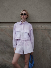 a lady wears a sporty crop jacket with matching shorts